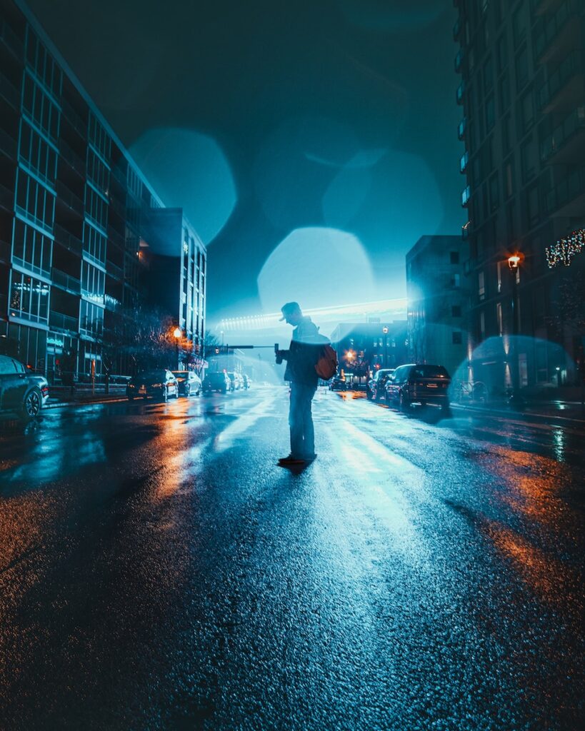 Person Standing on Road Between Buildings